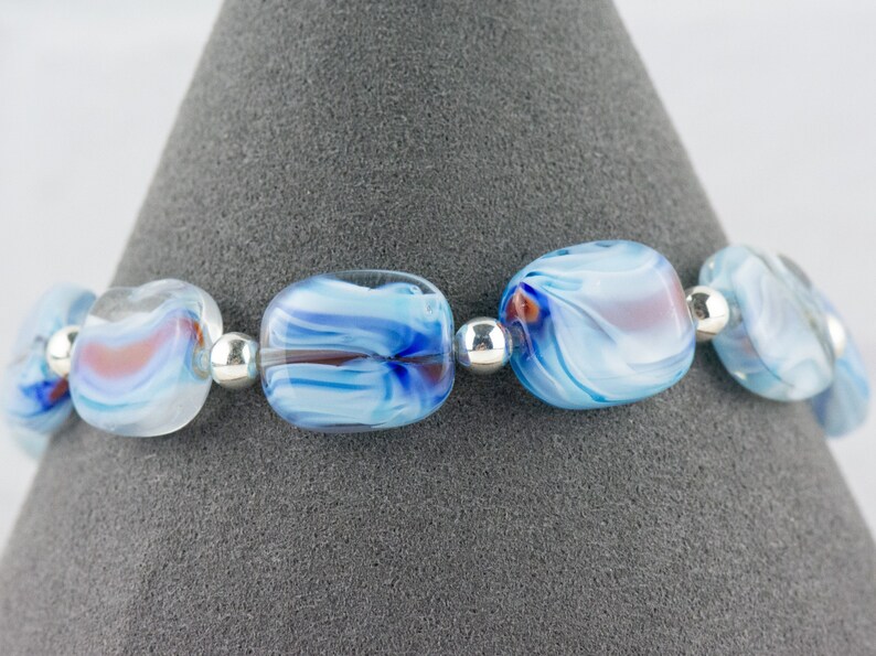 May include: A bracelet made with blue and white glass beads with silver spacer beads. The beads have a swirling pattern.