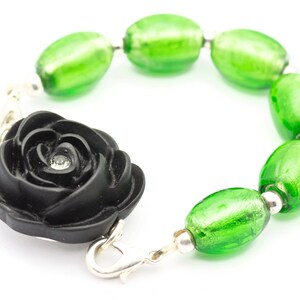 May include: A black rose charm bracelet with green glass beads. The rose has a small rhinestone in the center.