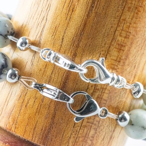 Peut inclure: Un bracelet en perles de pierre marbr&eacute;es blanc et noir avec un fermoir argent&eacute; et une cha&icirc;ne d'extension.