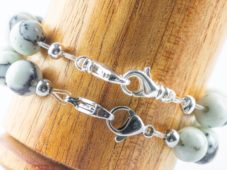 Peut inclure: Un bracelet en perles de pierre marbr&eacute;es blanc et noir avec un fermoir argent&eacute; et une cha&icirc;ne d'extension.
