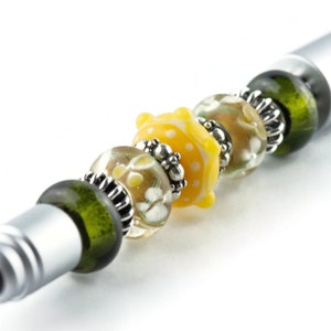 Peut inclure: Un stylo argent&eacute; avec une pointe tactile orn&eacute;e de perles de verre vertes, transparentes et jaunes. Les perles pr&eacute;sentent un motif floral et des accents argent&eacute;s.