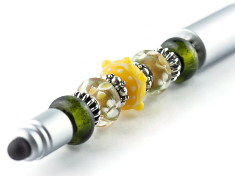 Peut inclure: Un stylo argent&eacute; avec une pointe tactile orn&eacute;e de perles de verre vertes, transparentes et jaunes. Les perles pr&eacute;sentent un motif floral et des accents argent&eacute;s.