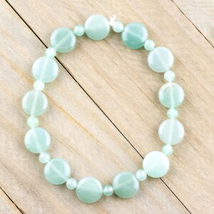 Peut inclure: Un bracelet en perles vert clair avec des perles rondes. Le bracelet est fait de pierre naturelle et est enfil&eacute; sur un cordon &eacute;lastique transparent.