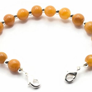 May include: A bracelet featuring amber-coloured beads and silver accents. The bracelet has a lobster clasp fastening.