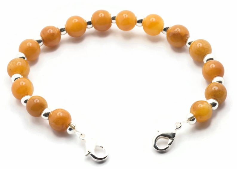 May include: A bracelet featuring amber-coloured beads and silver accents. The bracelet has a lobster clasp fastening.