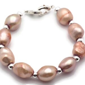 May include: A bracelet made of pink freshwater pearls and silver beads. The bracelet has a silver clasp.