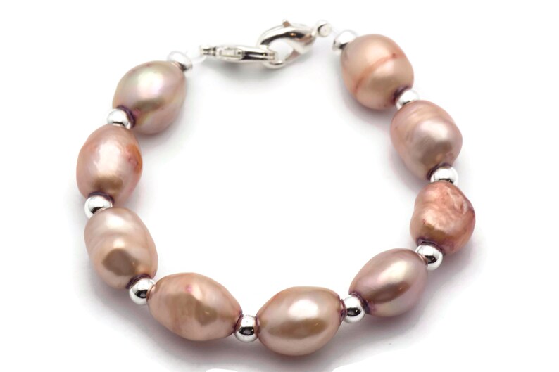 May include: A bracelet made of pink freshwater pearls and silver beads. The bracelet has a silver clasp.