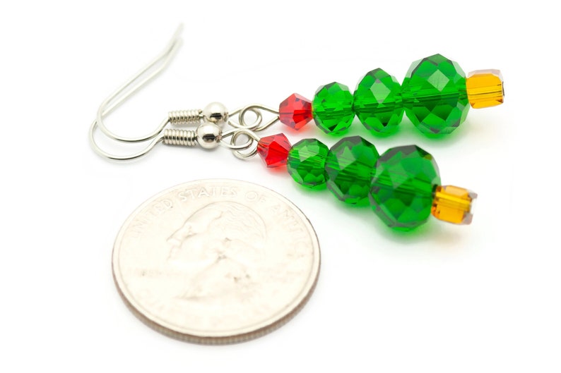 May include: A pair of green and red Christmas tree earrings with silver hooks. The earrings are made with faceted glass beads and are about the size of a quarter.