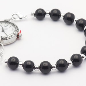 May include: A silver pocket watch with a black beaded chain. The watch face has black Roman numeral hour markers and a silver second hand.