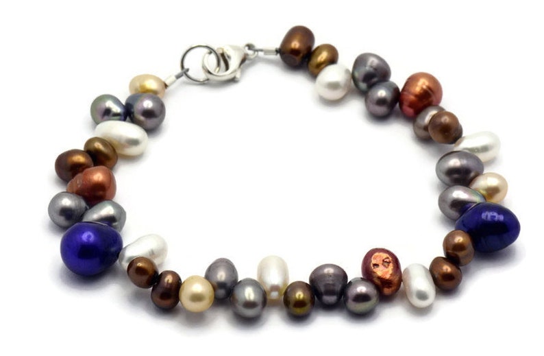 May include: A multi-colored freshwater pearl bracelet with a silver clasp. The pearls are various shades of white, brown, gray, blue, and copper.