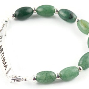 May include: A silver medical alert bracelet with the word "ASTHMA" engraved on it. The bracelet is made with green jade beads and silver spacers.