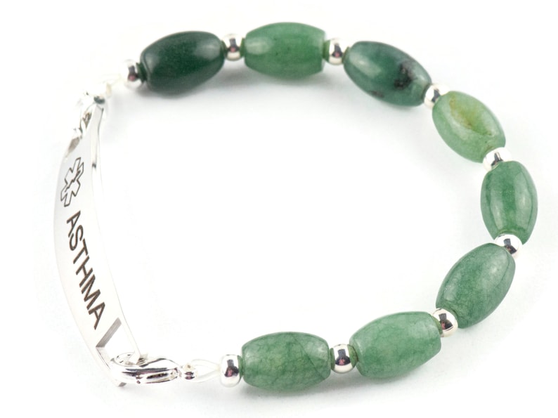 May include: A silver medical alert bracelet with the word "ASTHMA" engraved on it. The bracelet is made with green jade beads and silver spacers.