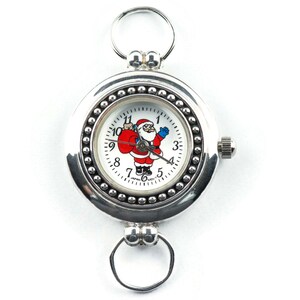 Puede incluir: Un reloj de bolsillo plateado con una esfera blanca y un dise&ntilde;o de Pap&aacute; Noel. El reloj tiene un bisel con cuentas y una cadena unida a la parte superior.