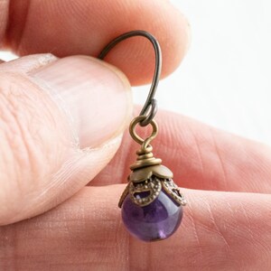 K&ouml;nnte beinhalten: Einzelner Amethyst-Ohrring mit antikfarbener Messing-Filigran-Kappe und Ohrhaken. Der Ohrring hat einen kleinen, runden, polierten, lila Edelstein. Die Metallkomponenten haben ein gealtertes, Vintage-Aussehen.