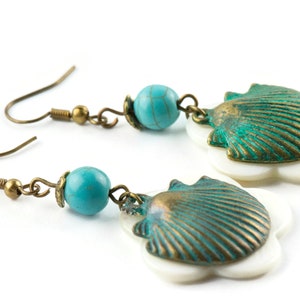 May include: A pair of turquoise and bronze earrings with a shell design. The earrings feature a turquoise bead and a bronze shell with a white flower-shaped base.