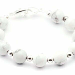 May include: A white howlite beaded bracelet with silver-tone details. The bracelet features round, marbled white beads and smaller silver beads. A silver clasp secures the bracelet.