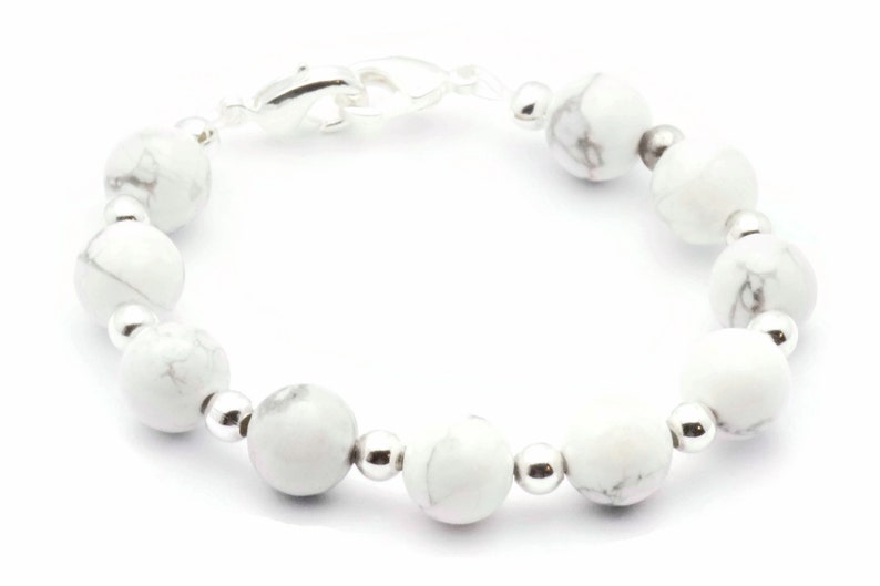 May include: A white howlite beaded bracelet with silver-tone details. The bracelet features round, marbled white beads and smaller silver beads. A silver clasp secures the bracelet.