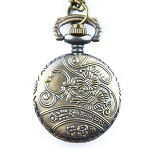 May include: A gold and silver pocket watch with an ornate floral design on the face.