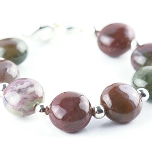 May include: A bracelet made of brown, green, and white agate beads with silver spacers.