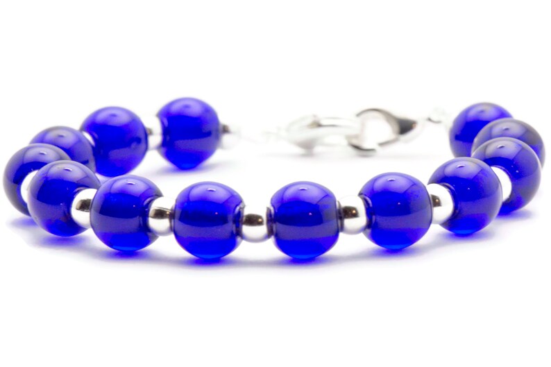 May include: A blue glass bead bracelet with silver spacers. The bracelet has a silver clasp.