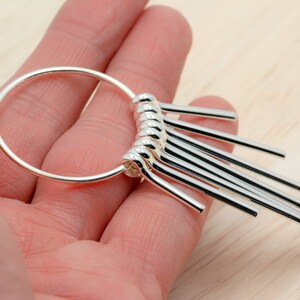 Puede incluir: Pendientes de aro de plata con una franja colgante de varillas de plata.