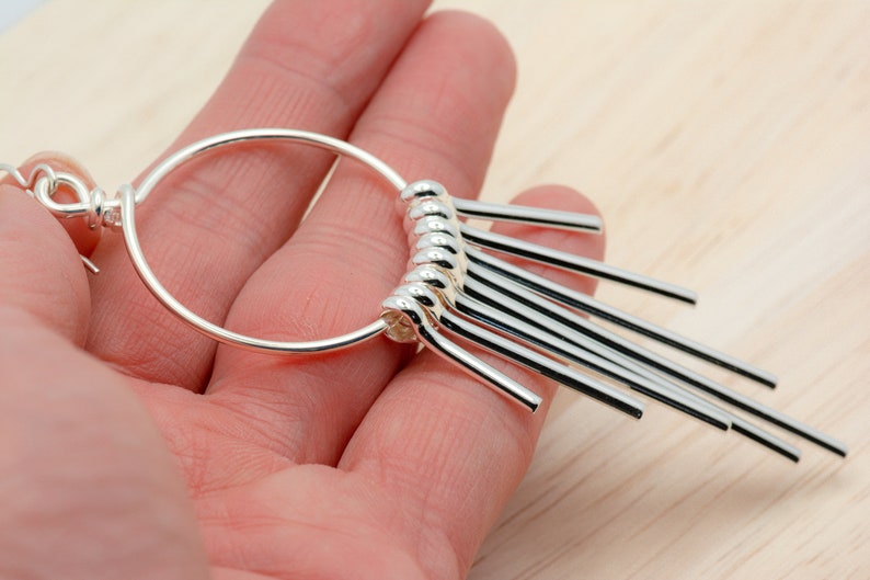 Puede incluir: Pendientes de aro de plata con una franja colgante de varillas de plata.