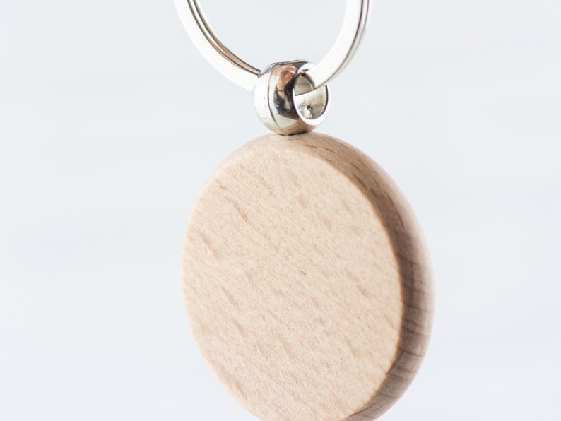 Op de afbeelding: Een ronde, houten sleutelhanger met een zilveren ring. De sleutelhanger is leeg en kan worden gepersonaliseerd.