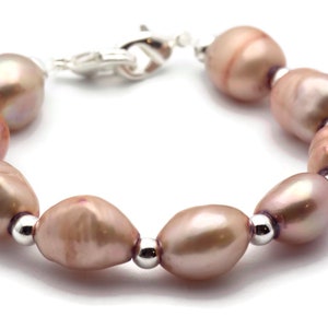 May include: A bracelet made of pink freshwater pearls and silver beads. The bracelet has a silver clasp.