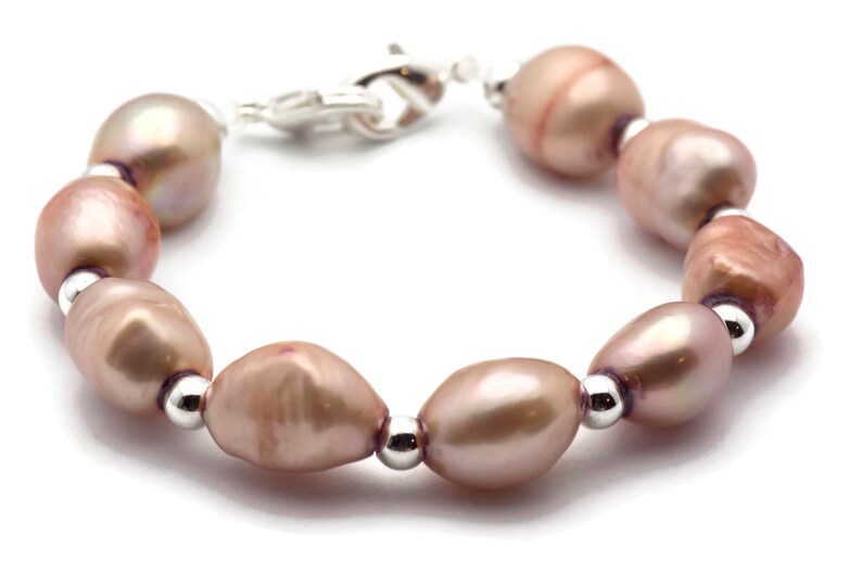 May include: A bracelet made of pink freshwater pearls and silver beads. The bracelet has a silver clasp.