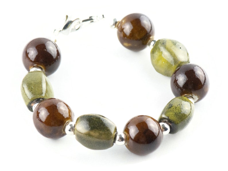 May include: A bracelet made of brown and green ceramic beads with silver accents.