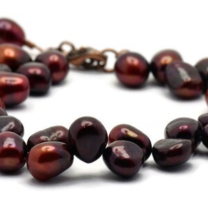 May include: A bracelet made of dark red pearls with a copper clasp.