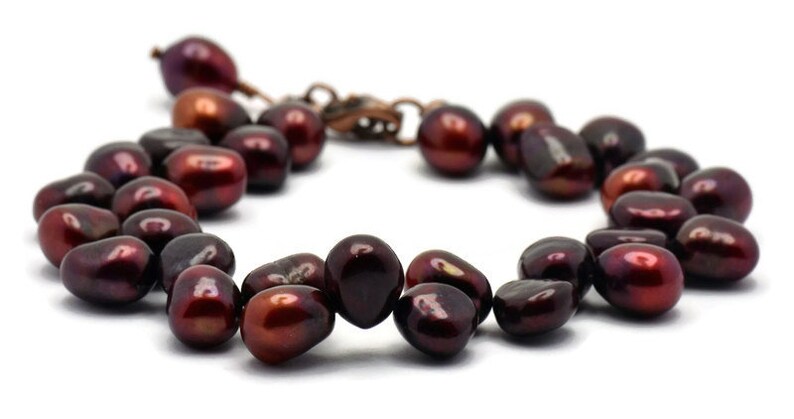 May include: A bracelet made of dark red pearls with a copper clasp.