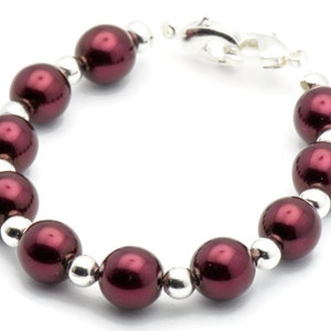 May include: A burgundy pearl bracelet with silver beads and a silver clasp.