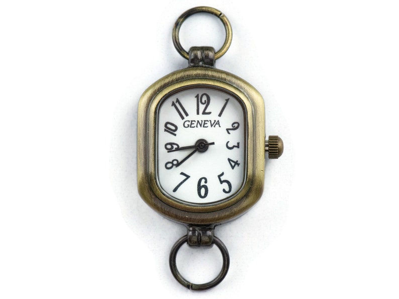 Pu&ograve; includere: Un quadrante di orologio di forma quadrata di colore oro antico con numeri romani neri e sfondo bianco. Il quadrante dell'orologio dice "GENEVA" nella parte superiore. L'orologio ha un anello nella parte superiore e inferiore per fissarlo a una catena o un braccialetto.