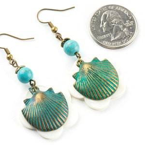 May include: A pair of turquoise and green shell earrings with a white shell accent. The earrings are made with bronze-coloured metal and have a hook closure.