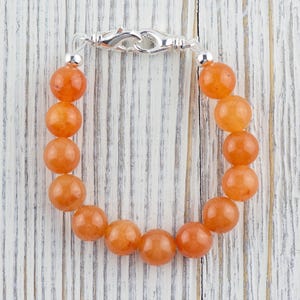 Op de afbeelding: Een armband gemaakt met oranje carneol kralen en een zilveren sluiting.
