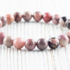 May include: A pink and gray gemstone bracelet with round beads.