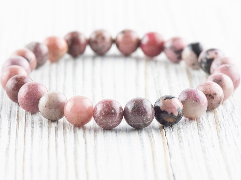 May include: A pink and gray gemstone bracelet with round beads.