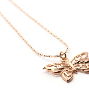 Peut inclure: Un collier d&eacute;licat en cha&icirc;ne dor&eacute;e avec un pendentif papillon d&eacute;taill&eacute;. Le papillon est fait de m&eacute;tal ajour&eacute; et pr&eacute;sente un design d&eacute;licat et complexe.
