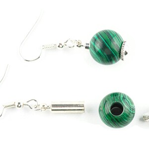 May include: A pair of silver earrings with green malachite beads. The earrings are made with a silver hook and a silver bead.