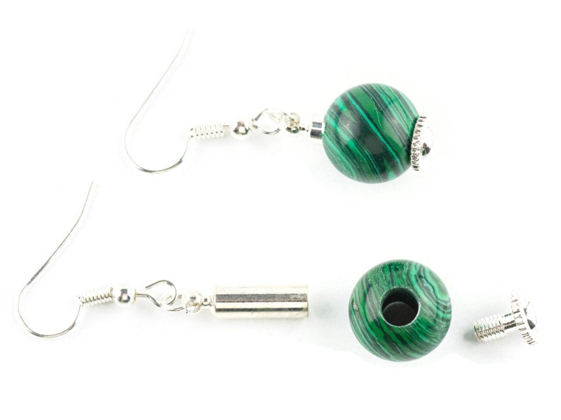 May include: A pair of silver earrings with green malachite beads. The earrings are made with a silver hook and a silver bead.