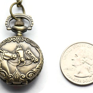 Puede incluir: Reloj de bolsillo antiguo de color dorado con un dise&ntilde;o de tres cabezas de caballo en la parte delantera. El reloj es aproximadamente del tama&ntilde;o de una moneda de 25 c&eacute;ntimos de euro.