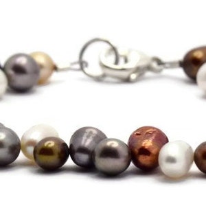 May include: A multi-colored pearl bracelet with a silver clasp. The bracelet features a variety of pearl shapes and sizes, including round, oval, and teardrop. The pearls are in shades of white, cream, brown, and purple.
