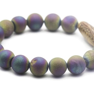 May include: A bracelet made of iridescent agate beads with a wooden bead accent. The beads are a mix of green, purple, and blue.