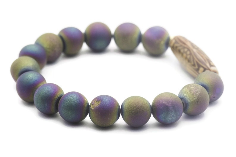 May include: A bracelet made of iridescent agate beads with a wooden bead accent. The beads are a mix of green, purple, and blue.
