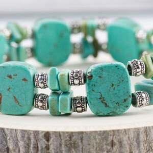 Op de afbeelding: Een turquoise en zilveren armband met vierkante en rechthoekige turquoise stenen. De armband is gemaakt van natuurlijke turquoise en zilveren kralen.
