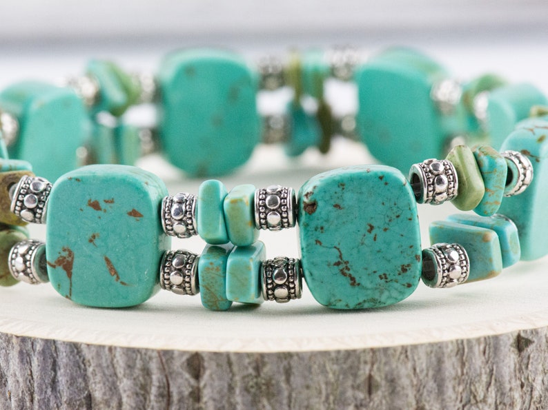 Op de afbeelding: Een turquoise en zilveren armband met vierkante en rechthoekige turquoise stenen. De armband is gemaakt van natuurlijke turquoise en zilveren kralen.