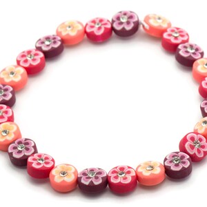 K&ouml;nnte beinhalten: Eine bunte Perlenkette mit blumenf&ouml;rmigen Perlen in Rosa-, Orange- und Lilat&ouml;nen. Jede Perle hat einen kleinen Strassstein in der Mitte.