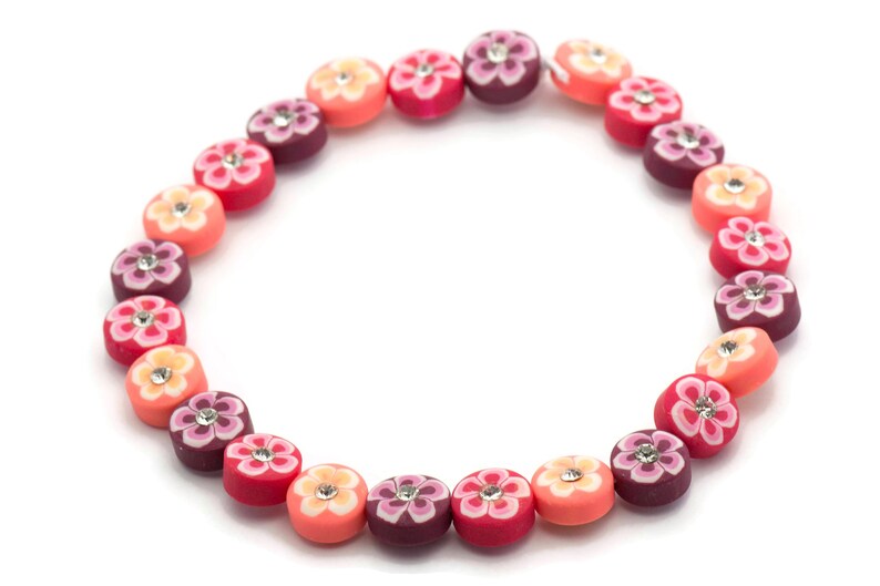 K&ouml;nnte beinhalten: Eine bunte Perlenkette mit blumenf&ouml;rmigen Perlen in Rosa-, Orange- und Lilat&ouml;nen. Jede Perle hat einen kleinen Strassstein in der Mitte.