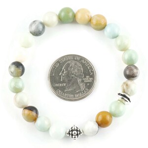 Black Gold Amazonite Genuine Gemstone Stretch Bracelet on white background. Amazonite beads are multicolor earth-tones. Center bead is a silver Bali style bead. Quarter in center of bracelet is for a size reference.